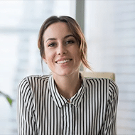 A smiling woman in a striped shirt sitting at a desk, using ai customer service software.